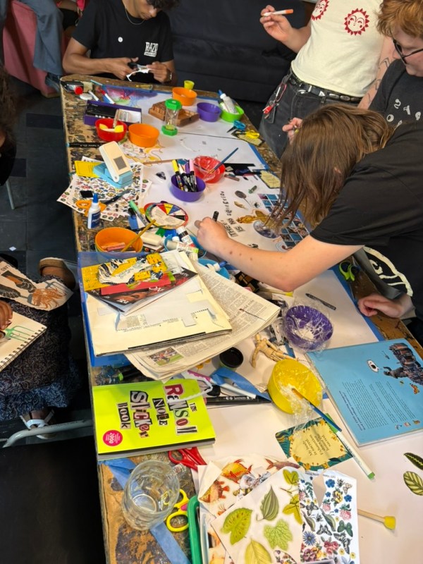 A craft table with colourful craft materials and people working on it